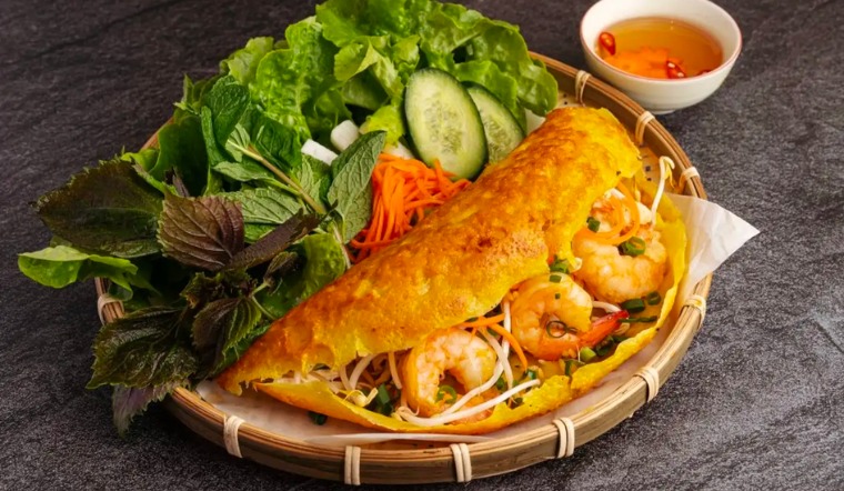 A delicious Banh Xeo consists of crispy fried batter, fresh vegetables, and various fillings, such as pork and seafood like shrimp and squid
